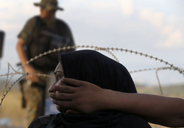 A Macedonian riot policeman stands guard as a Syrian refugee woman sits behind barbed-wire at the Greek-Macedonian border, near the village of Idomeni, August 21, 2015. Macedonian police fired tear gas and stun grenades to drive migrants and refugees back from its southern border from Greece on Friday but crowds continued to build up at a new bottleneck in an increasingly desperate flight to western Europe. At least 10 people were hurt in the brief flare-up, a day after the impoverished Balkan country declared a state of emergency on its border to halt a daily influx of up to 2,000 Syrians, Afghans, Iraqis and others heading north. REUTERS/Yannis Behrakis A Macedonian riot policeman stands guard as a Syrian refugee woman sits behind barbed-wire at the Greek-Macedonian border, near the village of Idomeni, August 21, 2015. Macedonian police fired tear gas and stun grenades to drive migrants and refugees back from its southern border from Greece on Friday but crowds continued to build up at a new bottleneck in an increasingly desperate flight to western Europe. At least 10 people were hurt in the brief flare-up, a day after the impoverished Balkan country declared a state of emergency on its border to halt a daily influx of up to 2,000 Syrians, Afghans, Iraqis and others heading north. REUTERS/Yannis Behrakis