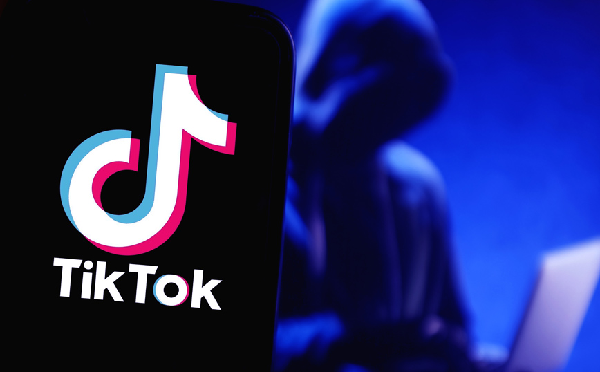 Οθόνη που γράφγει TikTok και μία μορφή με κουκούλα Οθόνη που γράφγει TikTok και μία μορφή με κουκούλα