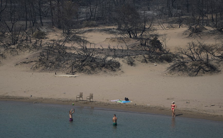 Η απόκοσμη εικόνα από παραλία της Ρόδου που κάνει τον γύρο του κόσμου: Λουόμενοι με φόντο τα καμμένα
