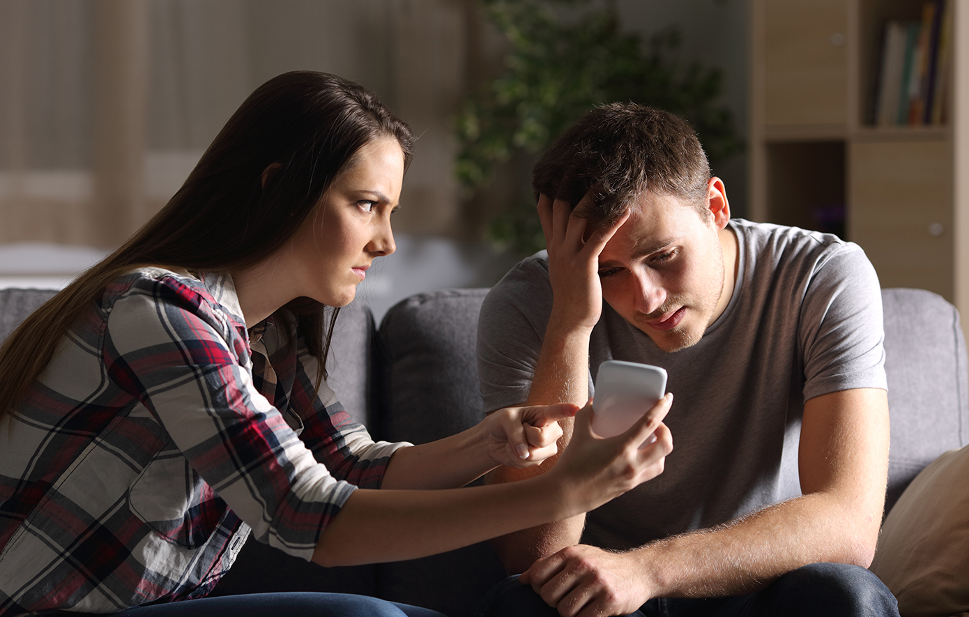 Γυναίκα δείχνει κάτι στον άντρα της στο κινητό θυμωμένη Γυναίκα δείχνει κάτι στον άντρα της στο κινητό θυμωμένη