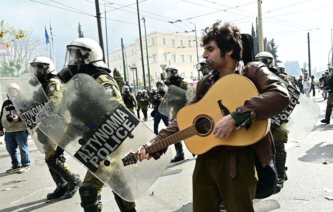 Διαδηλωτής παίζει κιθάρα δίπλα στα ΜΑΤ τη στιγμή των επεισοδίων στο Σύνταγμα &#8211; Δείτε φωτογραφίες