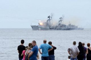 People gather to watch celebrations for Navy Day, as a Russian warship fires, in the far eastern city of Vladivostok