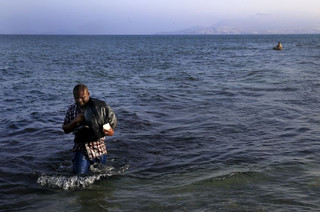 A migrant from Mali walks ashore on the Greek island of Kos after crossing a part of the Aegean Sea between Turkey and Greece, August 8, 2015.   The U.N refugee agency, UNHCR, estimates that Greece has received more than 107,000 refugees and migrants this year, more than double its 43,500 intake of 2014. REUTERS/Yannis Behrakis       TPX IMAGES OF THE DAY
