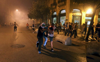 Protestors run during a protest against corruption and rubbish collection problems near the government palace in Beirut