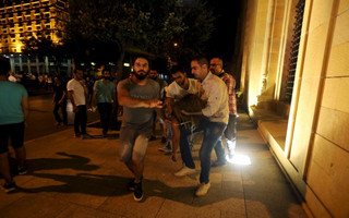 A wounded woman is carried by protestors during a protest against corruption and rubbish collection problems near the government palace in Beirut