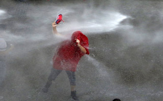 A Lebanese protester is sprayed with water during a protest against corruption and rubbish collection problems near the government palace in Beirut