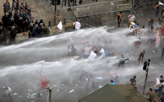 Lebanese protesters are sprayed with water during a protest against corruption and rubbish collection problems near the government palace in Beirut