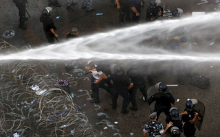 Lebanese protesters are sprayed with water as police arrest a man during a protest against corruption and rubbish collection problems near the government palace in Beirut