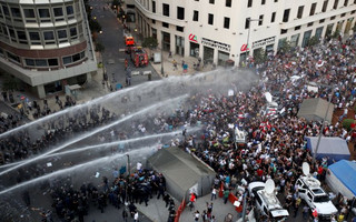 Lebanese protesters are sprayed with water during a protest against corruption in Beirut