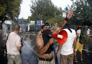 A migrant speaks in a megaphone as Hungarian riot police fires tear gas and water cannon at the border crossing with Serbia in Roszke, Hungary September 16, 2015. Hungarian police fired tear gas and water cannon at protesting migrants demanding they be allowed to enter from Serbia on Wednesday on the second day of a border crackdown. REUTERS/Marko Djurica