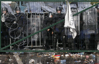 Hungarian riot police watches from behind a fence migrants protesting on the Serbian side of the border, near Roszke, Hungary September 16, 2015. Hungarian police fired tear gas and water cannon at protesting migrants demanding they be allowed to enter from Serbia on Wednesday on the second day of a border crackdown. REUTERS/Marko Djurica