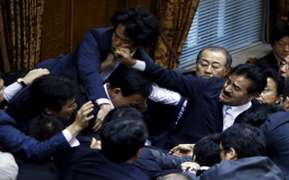 Lawmakers crowd around Konoike, chairman of the upper house special committee on security, as Sato of Japan's ruling Liberal Democratic Party's fist lands on opposition Democratic Party of Japan lawmaker Konishi at the parliament in Tokyo