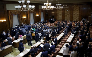 Lawmakers crowd around Yoshitada Konoike, chairman of the upper house special committee on security, during a vote at an upper house special committee session on security-related legislation at the parliament in Tokyo