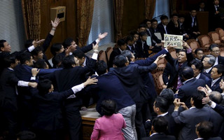 Japan's lawmaker Yamamoto of The People's Life Party & Taro Yamamoto and Friends holds a placard as lawmakers crowd around Yoshitada Konoike, chairman of the upper house special committee on security, at the parliament in Tokyo,