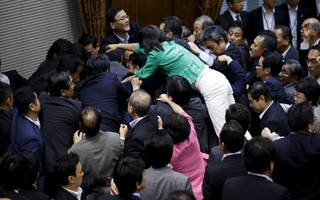 Opposition Democratic Party of Japan lawmaker Makiyama climbs over other lawmakers who are guarding Konoike, chairman of the upper house special committee on security, at the parliament in Tokyo