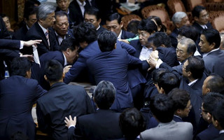 Opposition lawmakers crowd around Sato, deputation chairman of the upper house special committee on security, at an upper house special committee session on security-related legislation at the parliament in Tokyo