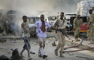 A Somali soldier helps a civilian who was wounded in a blast in the capital of Mogadishu, Somalia, Saturday, Oct. 14, 2017. A huge explosion from a truck bomb has killed at least 20 people in Somalia's capital, police said Saturday, as shaken residents called it the most powerful blast they'd heard in years. (AP Photo/Farah Abdi Warsameh)