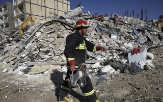 A rescue worker walks past the rubble of a collapsed building at an earthquake site in Sarpol-e-Zahab in western Iran, Tuesday, Nov. 14, 2017. Rescuers are digging through the debris of buildings fallen by Sunday's earthquake in the border region of Iran and Iraq. (AP Photo/Vahid Salemi)