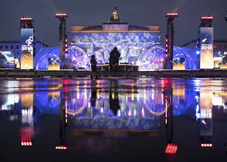 The illuminated Brandenburg Gate reflects in a puddle during a rehearsal prior to the New Year's Eve party of in Berlin, Germany, Saturday, Dec. 30, 2017. (Ralf Hirschberger/dpa via AP)