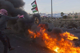 Palestinian protesters close a road with rocks and burning tires during clashes with Israeli troops following protests against U.S. President Donald Trump's decision to recognize Jerusalem as the capital of Israel, in the West Bank city of Ramallah, Saturday, Dec. 9, 2017. (AP Photo/Nasser Nasser)