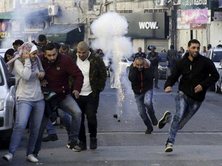 Palestinians run away from a sound bomb during clashes with Israeli security forces following a protest against U.S. President Donald Trump's decision to recognize Jerusalem as the capital of Israel in Jerusalem, Saturday, Dec.9, 2017.(AP Photo/Mahmoud Illean)