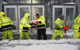 Workers place sand bags in front of Aquarium subway station to protect against flooding from Boston Harbor in Boston, Thursday, Jan. 4, 2018. A massive winter storm swept from the Carolinas to Maine on Thursday, dumping snow along the coast and bringing strong winds that will usher in possible record-breaking cold. (AP Photo/Michael Dwyer)