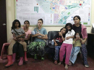 In this photo provided by Peru's police press office, Spanish citizen Patricia Aguilar, third from left, holds her baby at a police station, alongside two other Peruvian women and their children, after they were all rescued in San Martin de Pangoa, Peru, Thursday, July 5, 2018. Aguilar, a 19-year-old from Alicante, Spain, went missing in 2017 at age 16 and was rescued along with two Peruvian women while being held captive by Felix Manrique, a Peruvian who fathered their children. (Peru's police press office via AP)