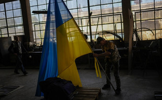  volunteer places a Ukraine flag on a metal bar at a facility producing material for Ukrainian soldiers in Zaporizhzhia, Ukraine, Friday, May 6, 2022